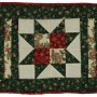 A variation on the sawtooth star pattern this time on a square tablemat. it is predominantly green with red and gold details.