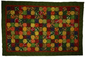 This shows a large patchwork quilt with a fruit and vegetable motif.  The colours are bright and are mainly red, yellow, green, blue and orange.