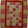 The full cheerful ducklings baby quilt in red and yellow. Red ducks appear next to bright gingham.