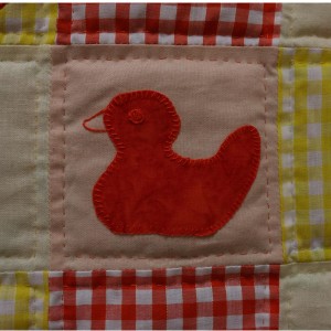 A detail of one duckling on the duckling quilt.
