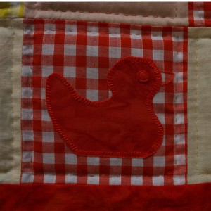 A single duckling on a red gingham background.