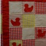 A detail of the ducklings quilt showing four of the red ducklings.