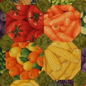 A detail showing tomatoes, carrots and corn, a bright cheerful quilt.